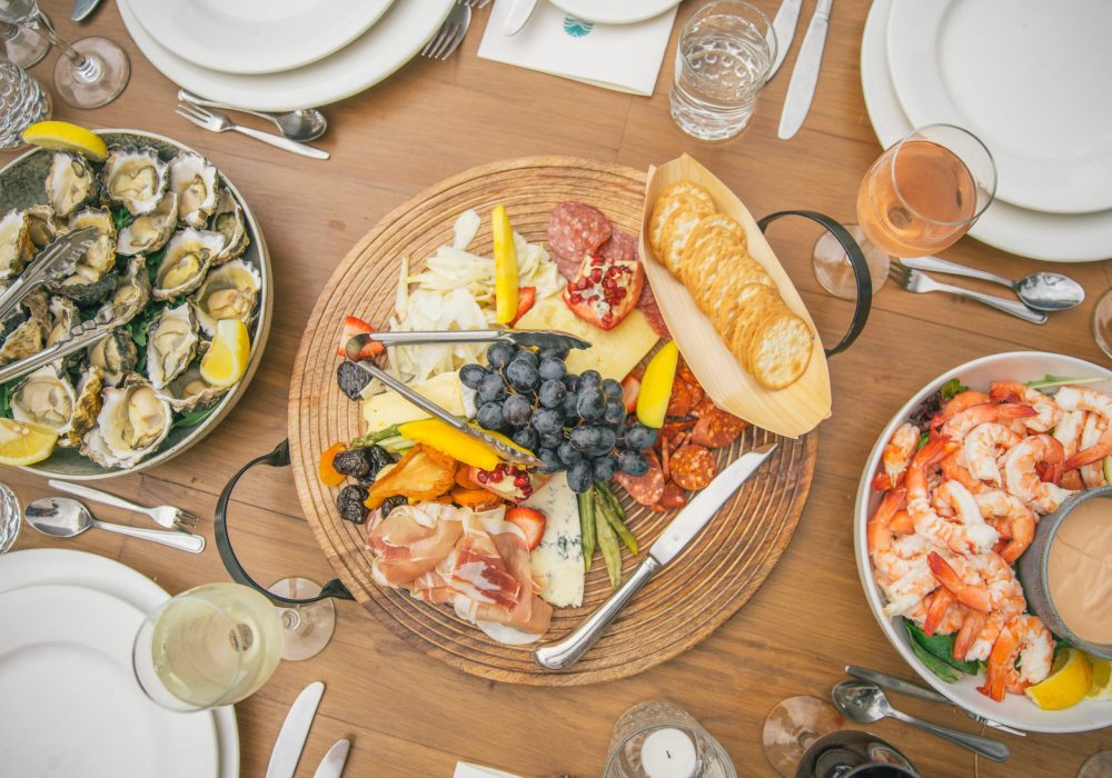A shared grazing platter of seafood, charcuterie and fruit with rose wine