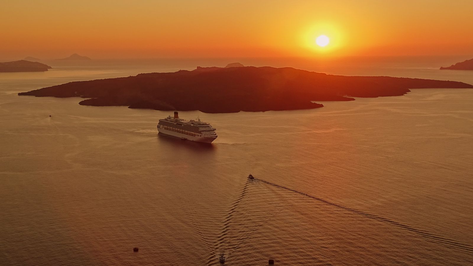 A cruise ship crossing a golden caldera at sunset